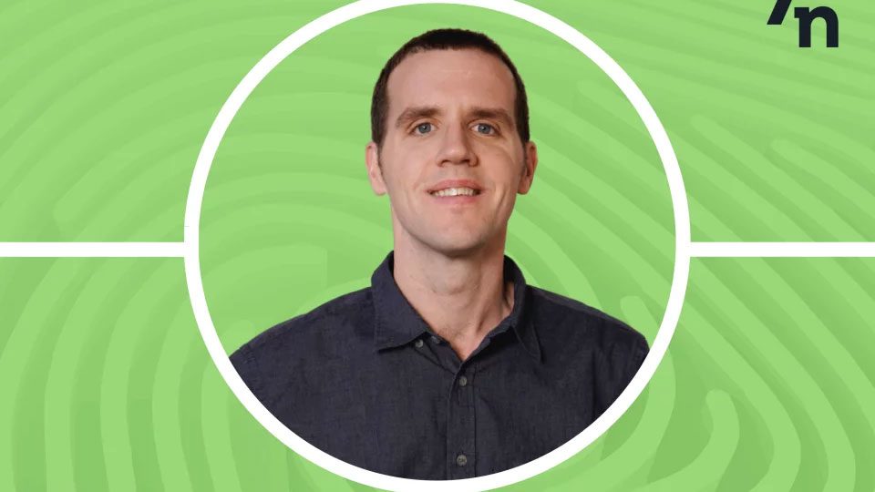 A person with short brown hair, wearing a dark button-up shirt, smiles against a bright green background with circular patterns. Framed by a white circle, they embody the friendly professionalism of CS Ops Central.