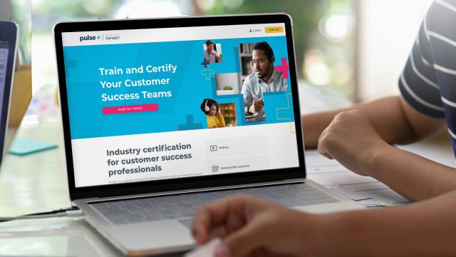 A person using a laptop displaying a website for training and certifying customer success teams. The screen showcases video call frames with people and text about industry certification, inviting the CS Ops Team to join CS operations professionals in enhancing their skills.