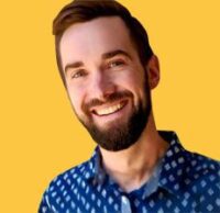 A bearded man smiles against a solid yellow background, embodying the cheer of CS Ops Central. He wears a blue patterned shirt, confidently blending casual style with operational flair.