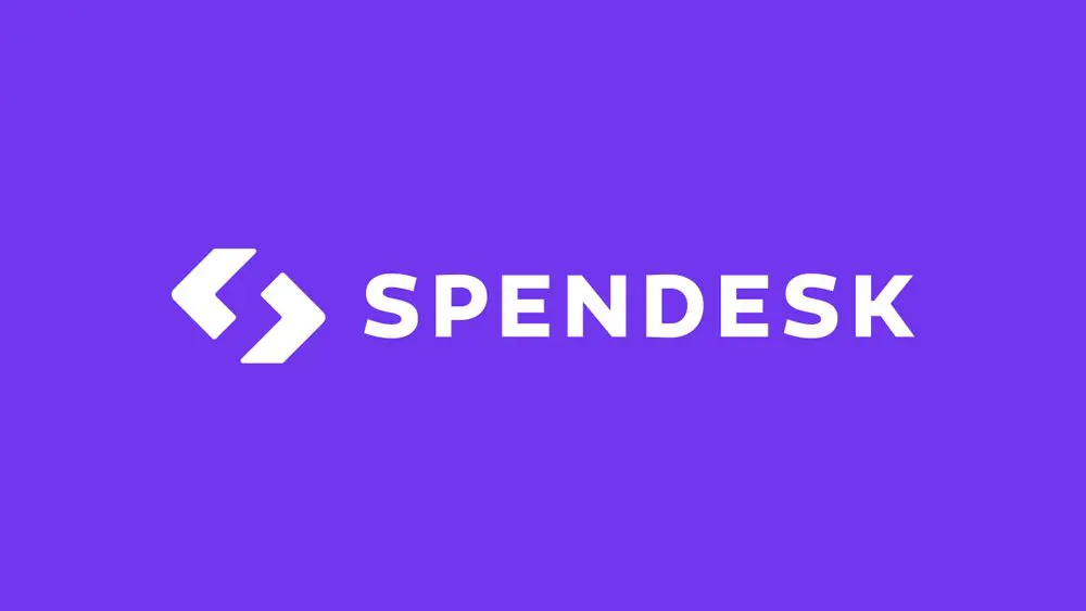 The image features the Spendesk logo, with white stylized arrows followed by the word 